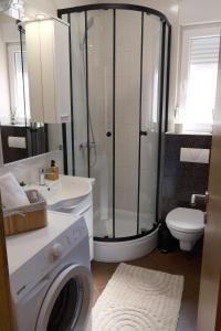 a bathroom with a shower and a washing machine at Bokun Gušta in Trogir