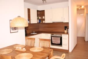 a kitchen with white cabinets and a wooden table at Gesine 3 in Nienhagen