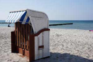 a bench on the beach with an umbrella at Bungalow Alex in Börgerende-Rethwisch +4 photos