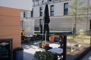 a patio with tables and chairs and an umbrella at Bungalow Alex in Börgerende-Rethwisch
