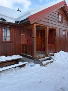 a wooden cabin with snow on the porch at Bakkestølveien 360 in Hol