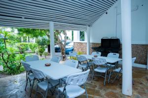 a patio with white tables and chairs and a piano at Coast Sun Gardens Cottage Adults Only in Msambweni