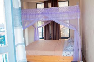 a bedroom with a canopy bed with purple curtains at Fido's Guesthouse in Ruhengeri