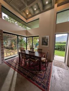 a dining room with a table and chairs and large windows at LA HACIENDA - MODERN, BRIGHT, STYLISH House with Private Pool in Cape Town