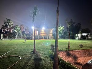 a building in a field with palm trees at night at Singhal's Farm House in Greater Noida +1 photo