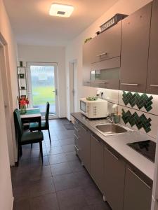 a kitchen with a sink and a table with a chair at Apartmány KK in Chvalovice