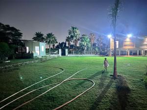 a woman walking in a field with a light pole at Singhal's Farm House in Greater Noida