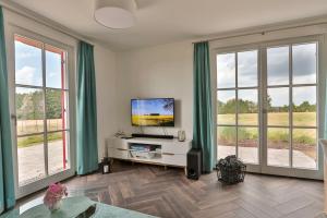 a living room with a flat screen tv and windows at FH Wiesenkieker in Güstow