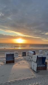a group of beach chairs on the beach at sunset at Appartementhaus Hoppe in Sylt