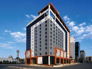 a tall white building with a clock tower in a city at Adagio Jeddah City Center in Jeddah