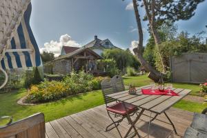a wooden table and chairs on a deck in a yard at Bungalow Koralle in Nienhagen
