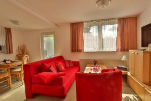 a living room with a red couch and a table at Bungalow Koralle in Nienhagen +13 photos