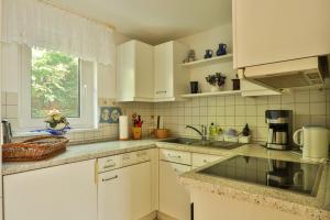 a kitchen with white cabinets and a sink and a window at Bungalow Koralle in Nienhagen