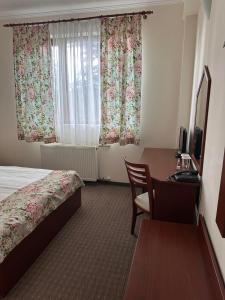 a hotel room with a bed and a desk and window at Dafovska Hotel in Pamporovo