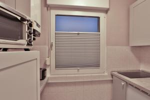 a kitchen with a window with blinds in it at Bungalow Paul in Nienhagen +19 photos