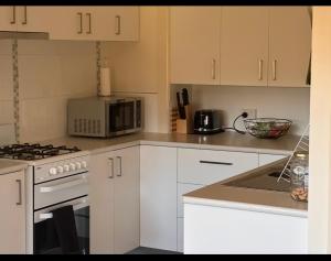 a kitchen with white cabinets and a microwave at Executive Accommodation Bairnsdale in Bairnsdale +3 photos