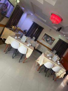 a dining room with tables and chairs and a television at Torax Lodge in Ibadan