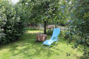 a blue chair sitting next to a tree stump at FeWo Lavendel in Kröpelin +6 photos