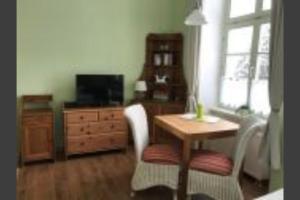 a living room with a table and a desk and a television at Herrenhaus Blengow App.1 in Blengow