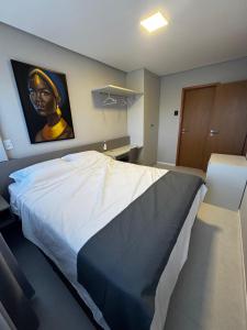 a bedroom with a large bed with a painting on the wall at Apartamento Ipioca Beach Life - Maceió in Maceió