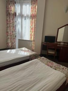 a hotel room with two beds and a desk and a window at Dafovska Hotel in Pamporovo