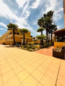 a courtyard with palm trees and a yellow building at Costa Norte in Alcalà de Xivert
