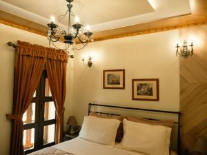 a bedroom with a bed with a chandelier and a window at Hotel SS KEKEZI in Gjirokastër