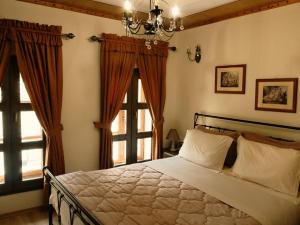 a bedroom with a bed with a chandelier and windows at Hotel SS KEKEZI in Gjirokastër