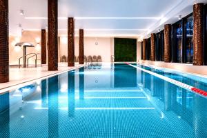 a swimming pool with blue water in a hotel at Blue & Green Masurian Hotel in Węgorzewo