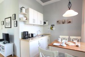 a kitchen with white cabinets and a wooden table at Herrenhaus Blengow App.02 in Blengow