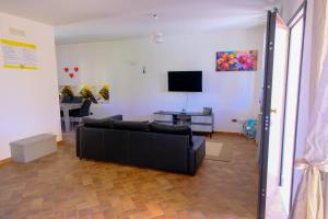 a living room with a black couch and a tv at Renée Guest House in Paestum