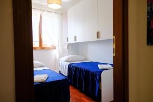 a room with two beds with blue sheets and a window at Renée Guest House in Paestum