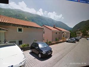 a black car parked in a parking lot with mountains in the background at Apartment Grandis in Škaljari