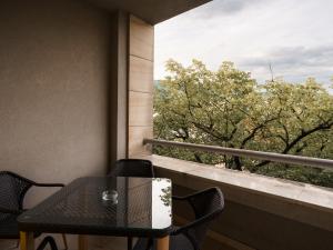 a table and chairs on a balcony with a view of trees at Rondo Condos by TORO in Mostar