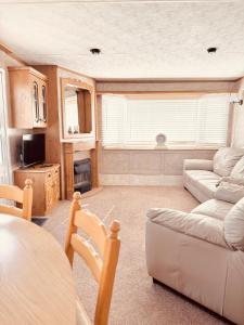 a living room with a couch and a table at 6 Birth Cosy caravan 134 Sealands in Ingoldmells