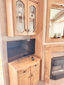 a kitchen with wooden cabinets and a tv at 6 Birth Cosy caravan 134 Sealands in Ingoldmells