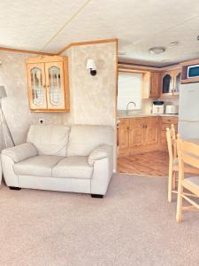 a living room with a white couch and a kitchen at 6 Birth Cosy caravan 134 Sealands in Ingoldmells