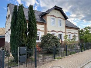 a house with a fence and two trees at Haus Wally - Ferienwohnungen in Klitten