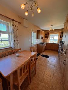 a kitchen and dining room with a wooden table and chairs at Beach Side House in Quilty in Quilty