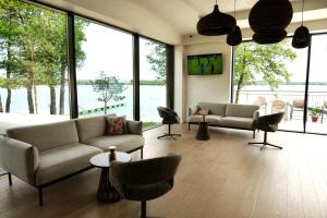 a living room with a couch and chairs and windows at Blue & Green Masurian Hotel in Węgorzewo