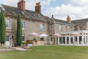 an old stone house with umbrellas in the yard at The Cavendish Hotel at Chatsworth in Baslow