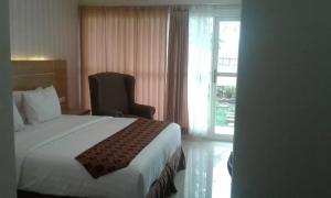 a bedroom with a bed and a chair and a window at Hotel Ella Tambolaka in Tambolaka Airport