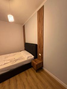 a small bedroom with a bed and a wooden floor at Gwin Hotel in Fier