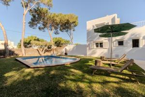 a pool with an umbrella and two chairs and a table at Villa Can Ferrer in the centre of Cala dOr in Cacla D'or