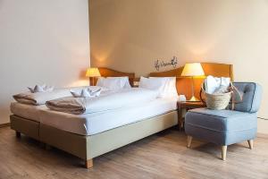 a bedroom with a large bed and a blue chair at Hotel Stoiser Graz -Parkplatz inbegriffen! in Graz +56 photos