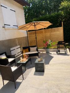 a patio with chairs and an umbrella and a table at Logement entier avec jacuzzi proche futuroscope in Naintré