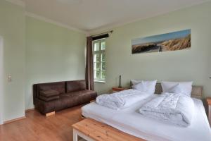 a bedroom with a white bed and a couch at Herrenhaus Blengow App.08 in Blengow