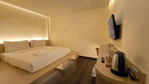 a hotel room with a bed and a television at Norns Silom Cafe & Stay in Bangkok
