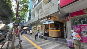 a street with people walking in front of a store at Norns Silom Cafe & Stay in Bangkok