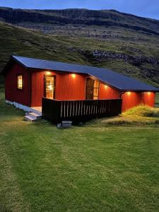 a red house with lights on it in a field at Saksun Mountain & Beach Cottage in Saksun +10 photos